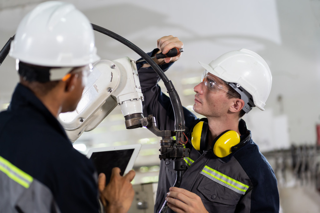 two men checking robotic arms in a construction site